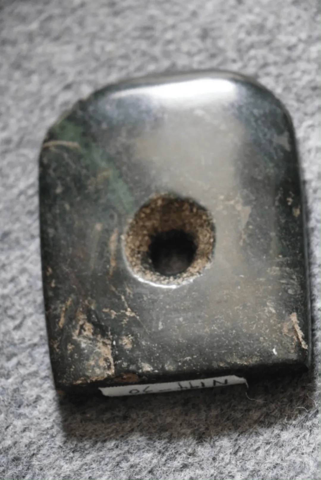 宁县博物馆藏仰韶玄玉钺,光照下表面出现黑中透绿的