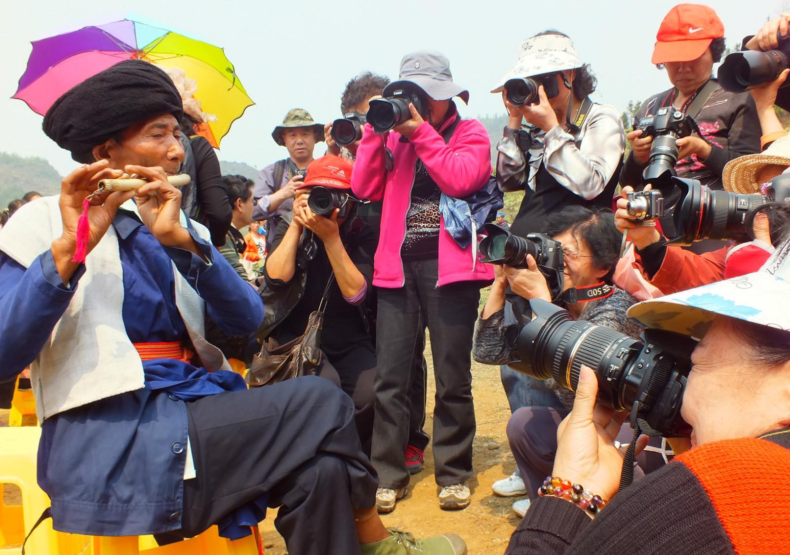 图说:100岁时朱进明老人在"夜郎竹王节"上吹奏笛子,引来"长枪短炮"