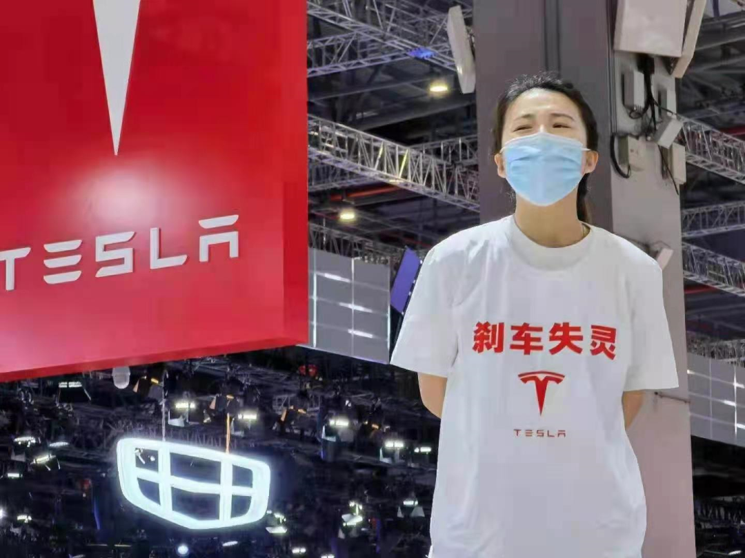 特斯拉的展台上出现一位穿着"刹车失灵"和特斯拉标识t恤的女士进行